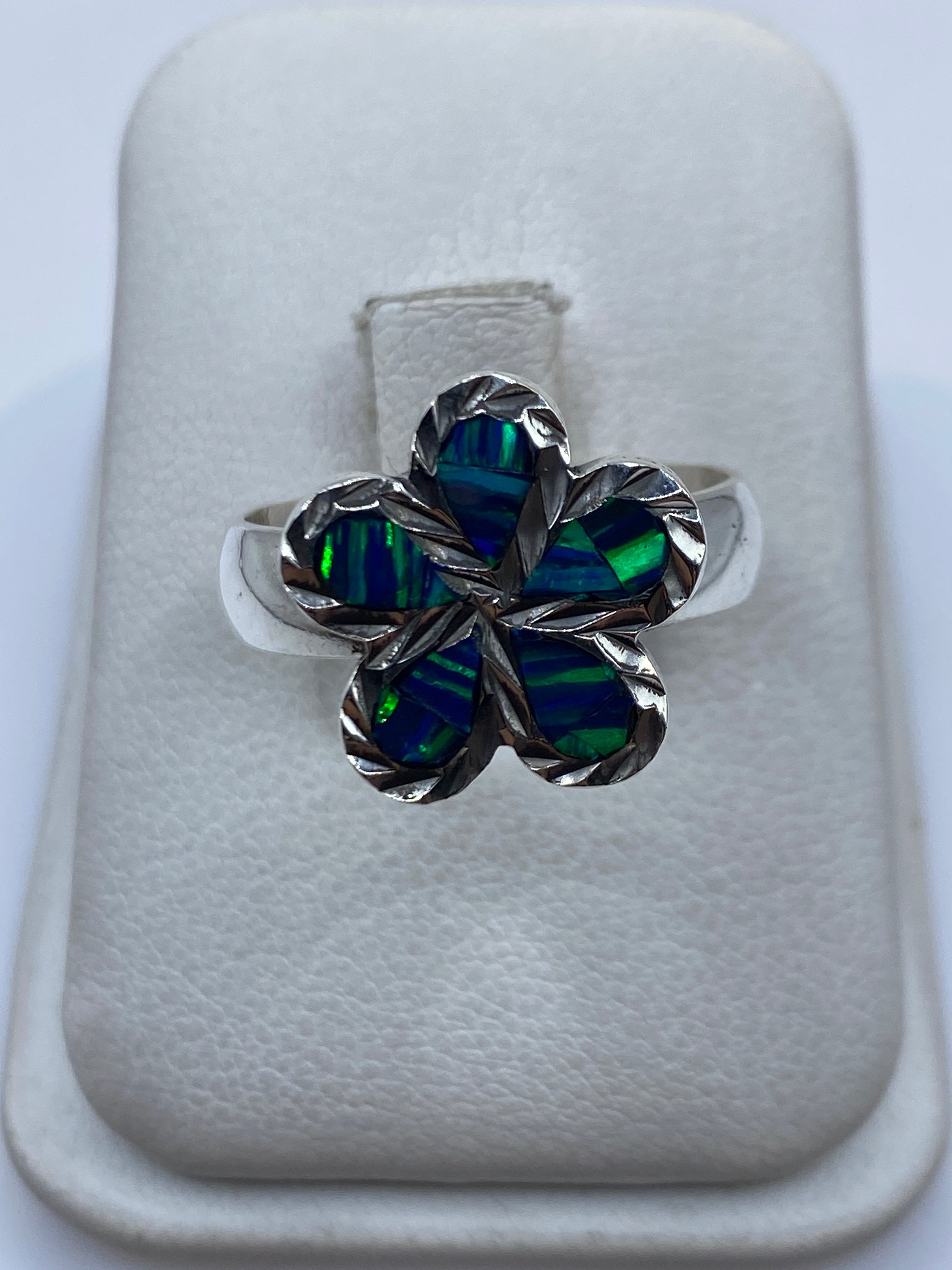 Anillo floral de plata .950 con ópal de fuego azul en la mano de una mujer