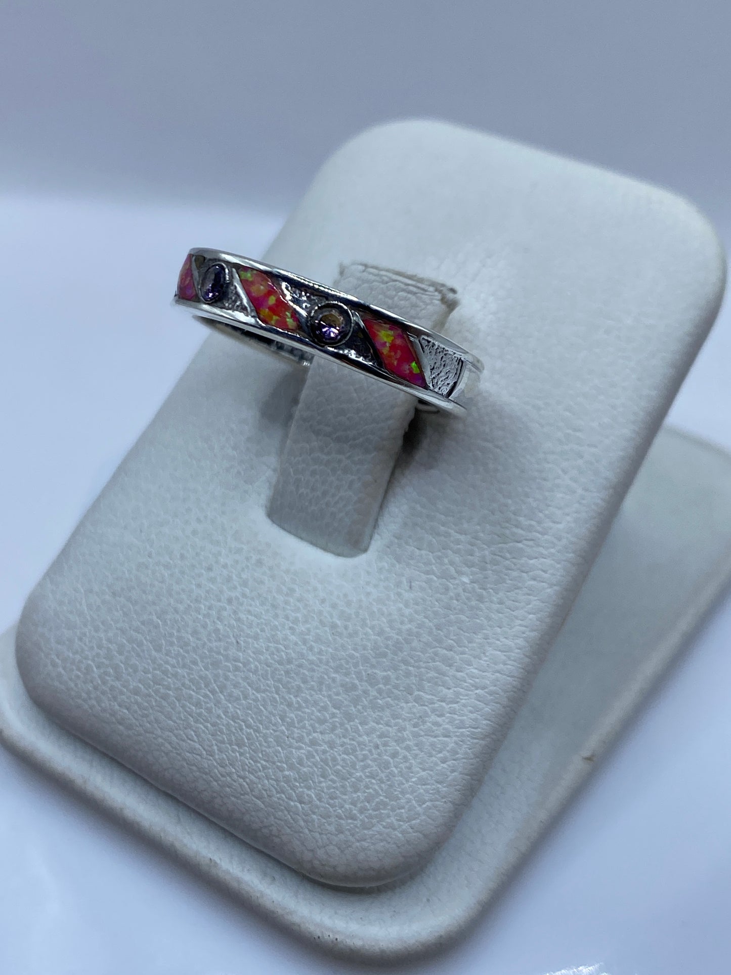 Detalle lateral del anillo mostrando el ópalo rosa con reflejos dorados y el engaste a mano