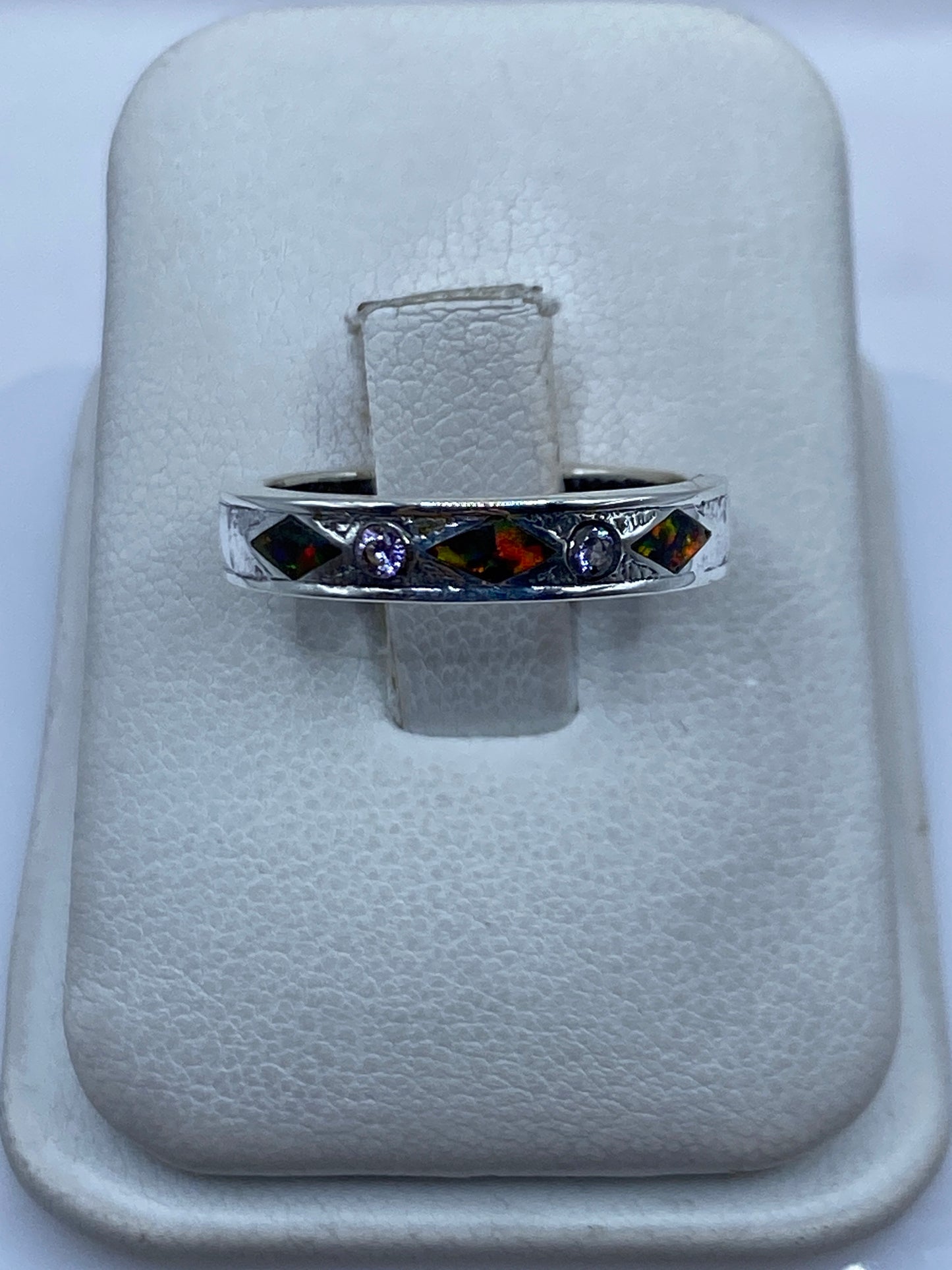 Anillo de plata .950 con ópalo de fuego multicolor en mano, mostrando el juego de colores rojo y naranja