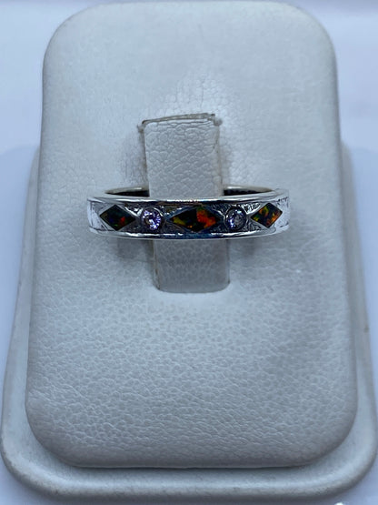 Anillo de plata .950 con ópalo de fuego multicolor en mano, mostrando el juego de colores rojo y naranja