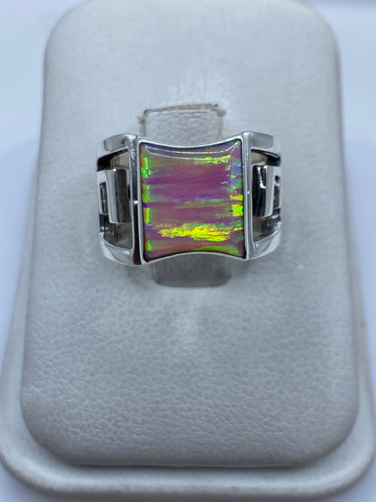 Anillo de plata .950 con ópalo de fuego rosa sobre dedo, mostrando reflejos verdes y dorados