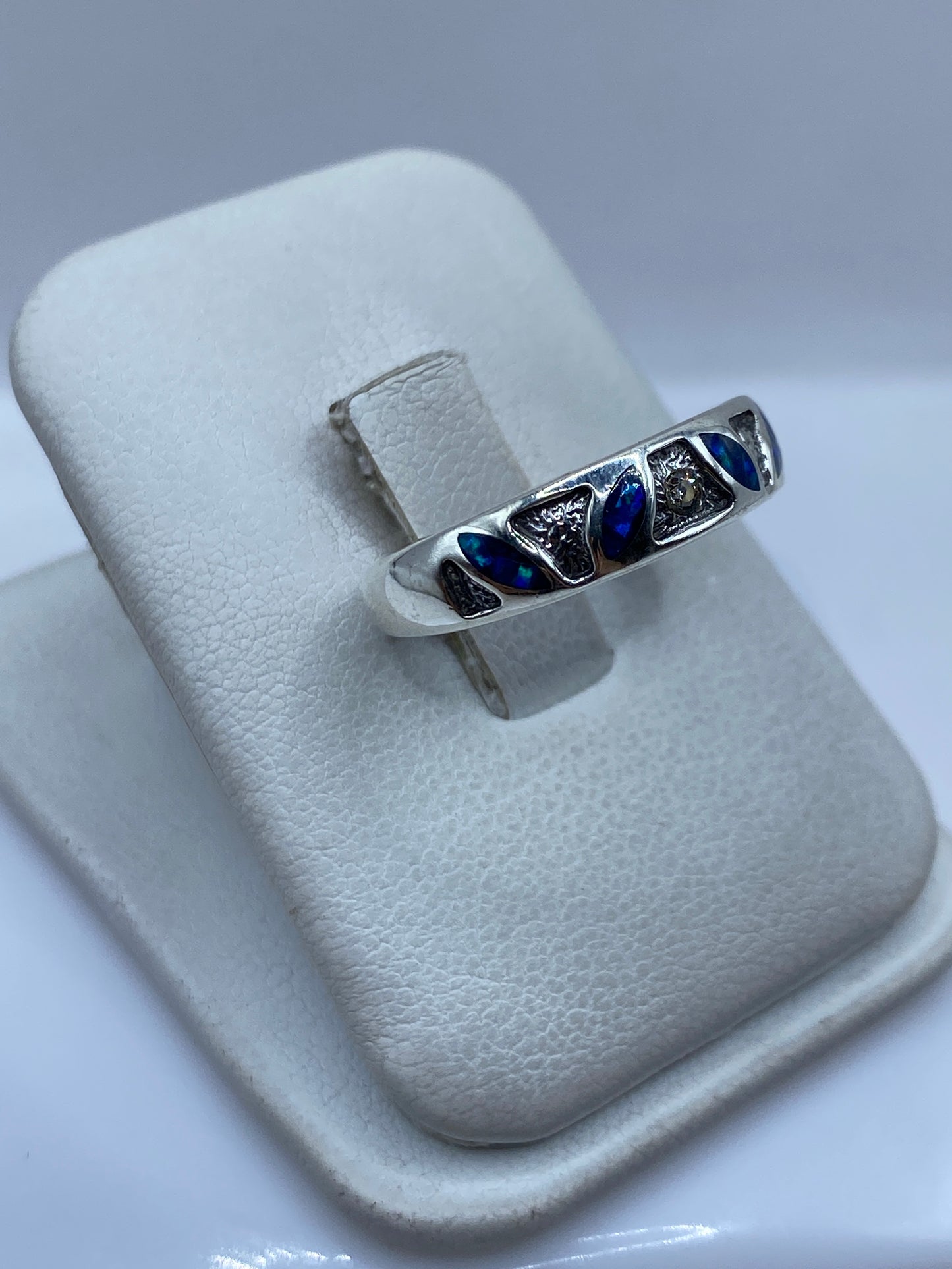 Anillo en la mano mostrando el ópalo azul reflejando la luz