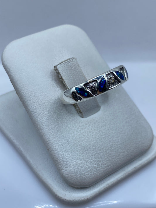 Anillo en la mano mostrando el ópalo azul reflejando la luz