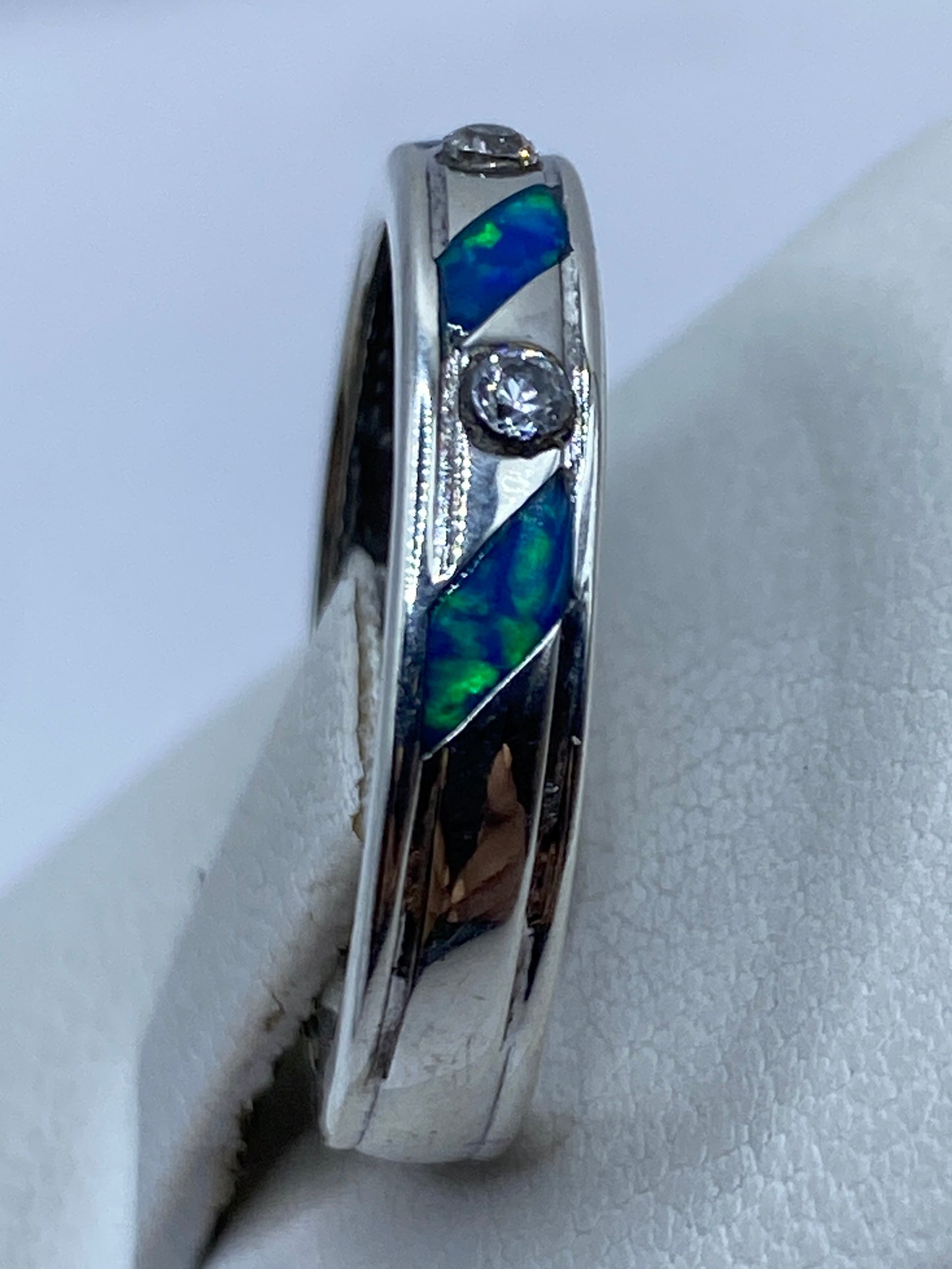 Anillo puesto en dedo mostrando los reflejos azul-verdosos de la piedra