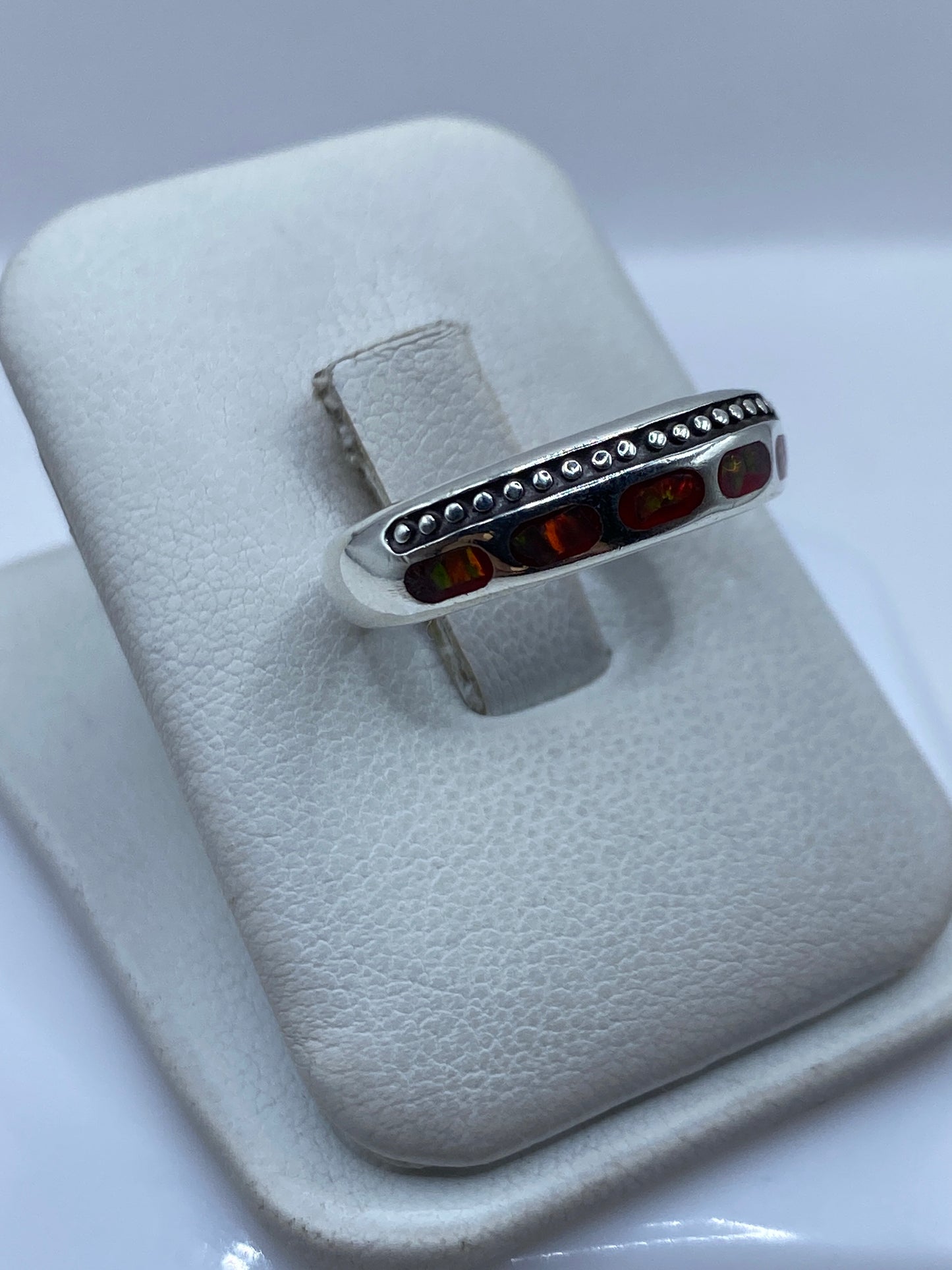Detalle lateral del anillo mostrando el ópalo de fuego con destellos anaranjados y verdes
