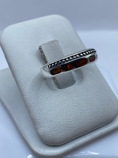 Detalle lateral del anillo mostrando el ópalo de fuego con destellos anaranjados y verdes