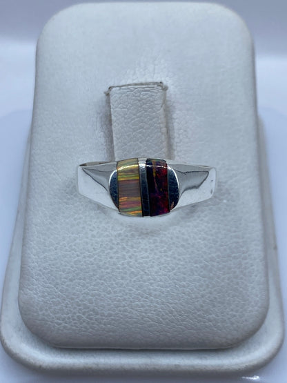 Anillo de plata con ópalo de fuego multicolor mostrando bandas de verde, naranja y rojo