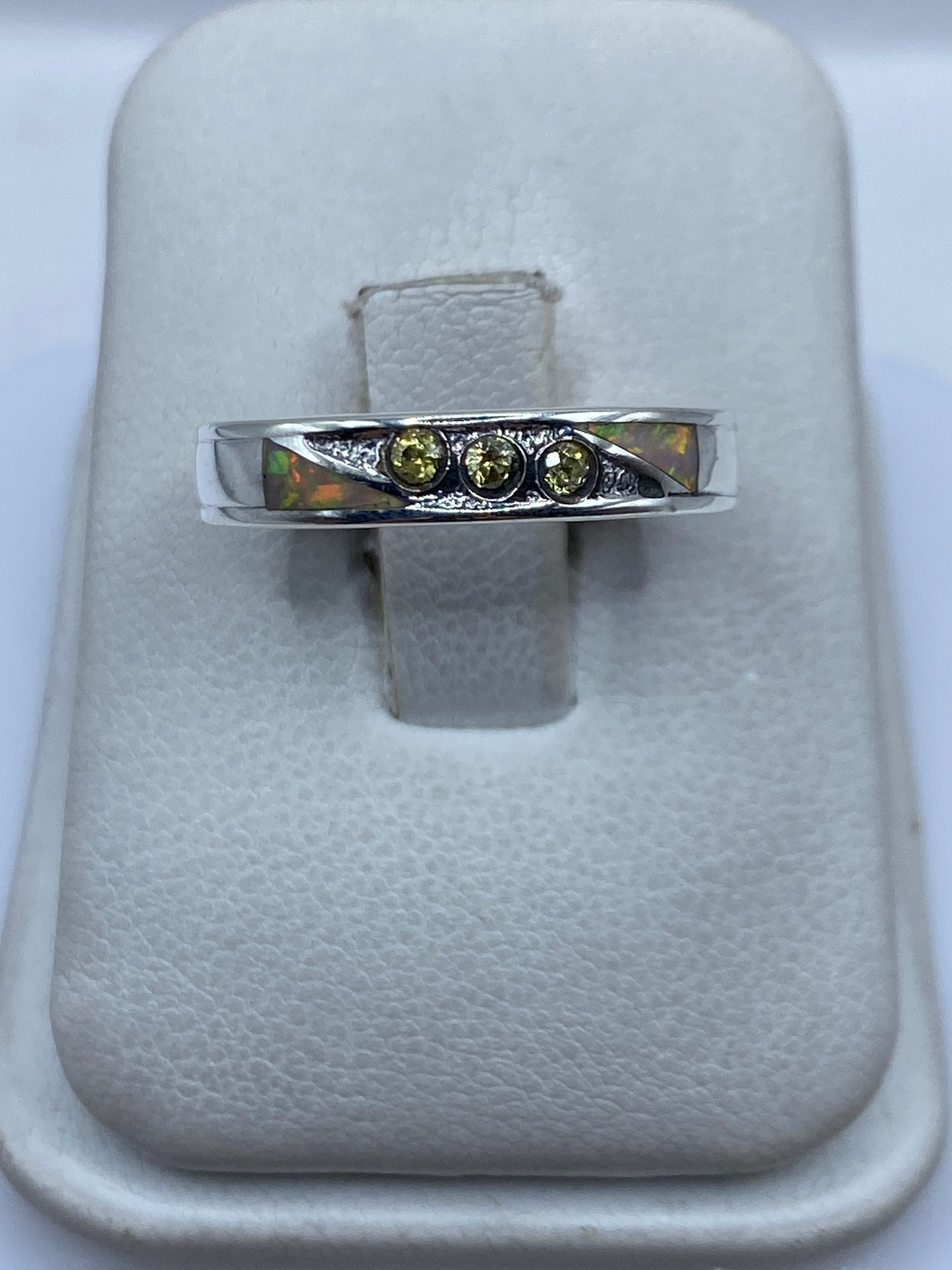 Anillo de plata .950 con ópalo de fuego multicolor en la mano, mostrando el juego de colores