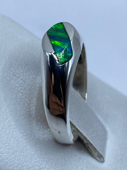 Anillo en dedo mostrando los destellos verdes del ópalo de fuego bajo luz natural