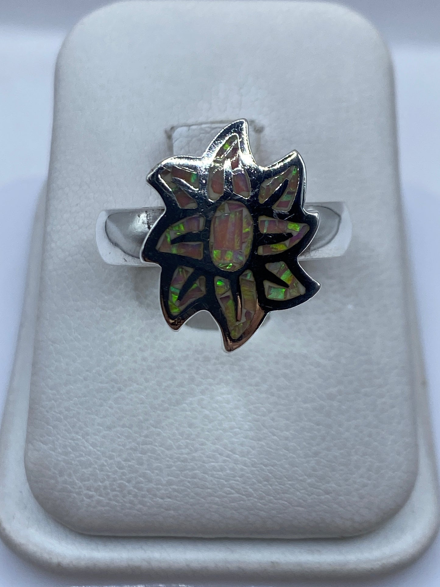 Anillo de plata con ópalo de fuego multicolor iridiscente en dedo de mujer