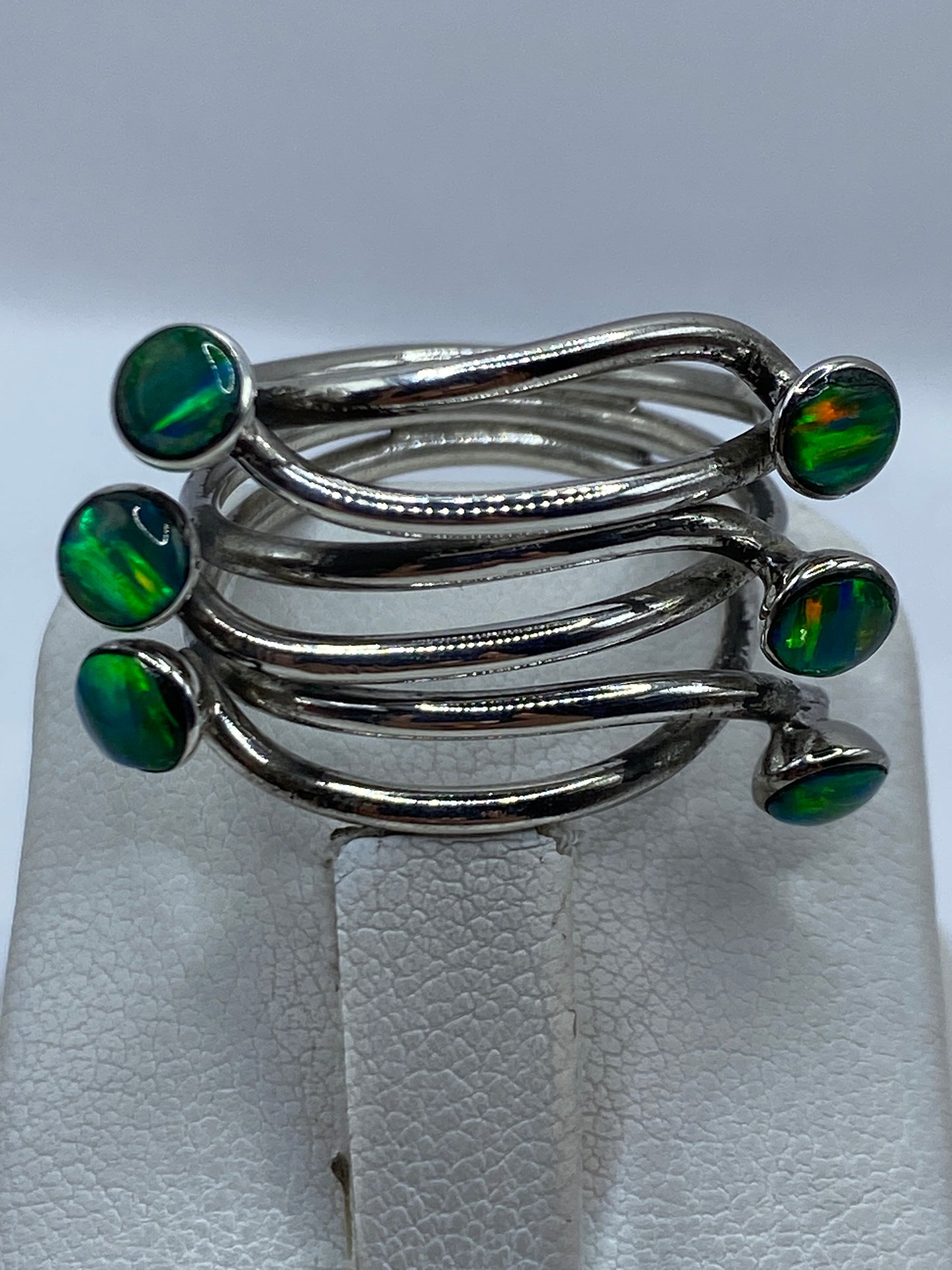 Anillo puesto en el dedo mostrando el color verde limón del ópalo a la luz