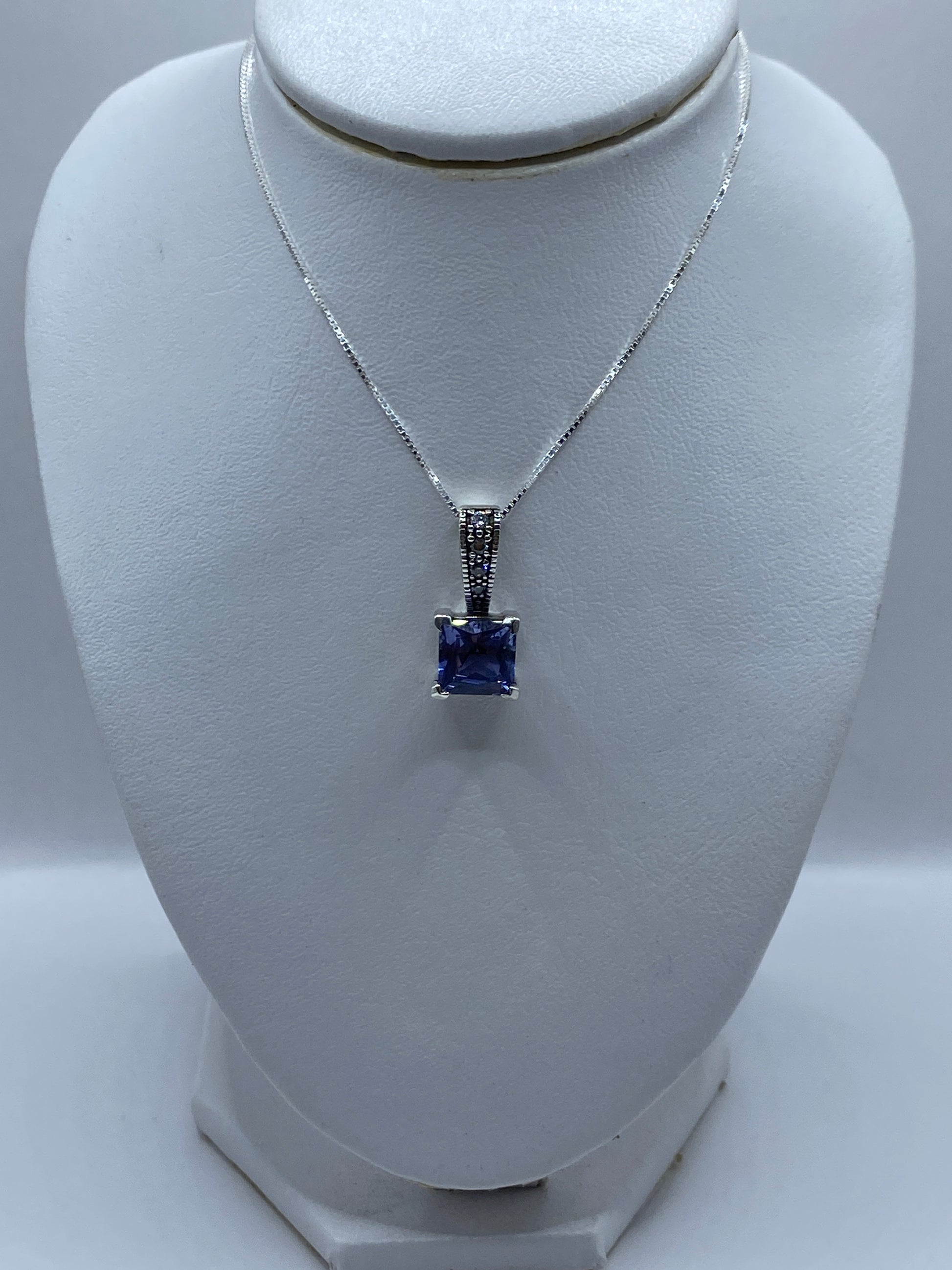 Detalle del dije mostrando la circonia talla brillante cuadrada lavanda y el engaste a mano