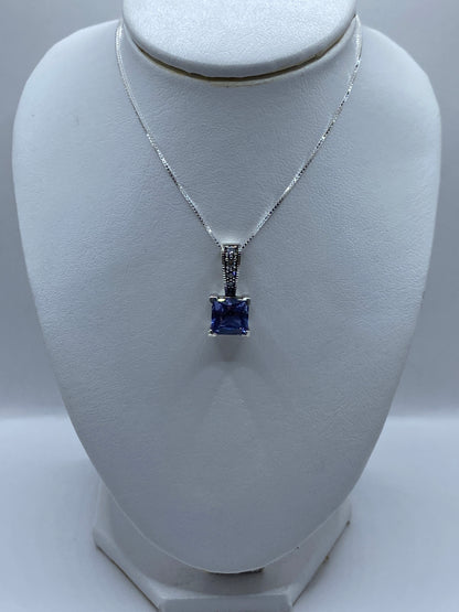 Detalle del dije mostrando la circonia talla brillante cuadrada lavanda y el engaste a mano