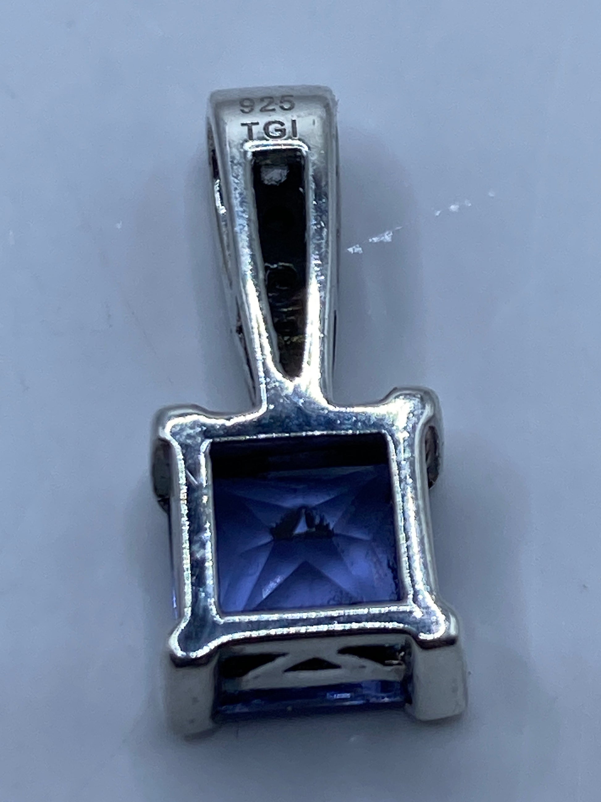 Dije de circonia lavanda sobre escala milimétrica — aproximadamente 10 mm de ancho