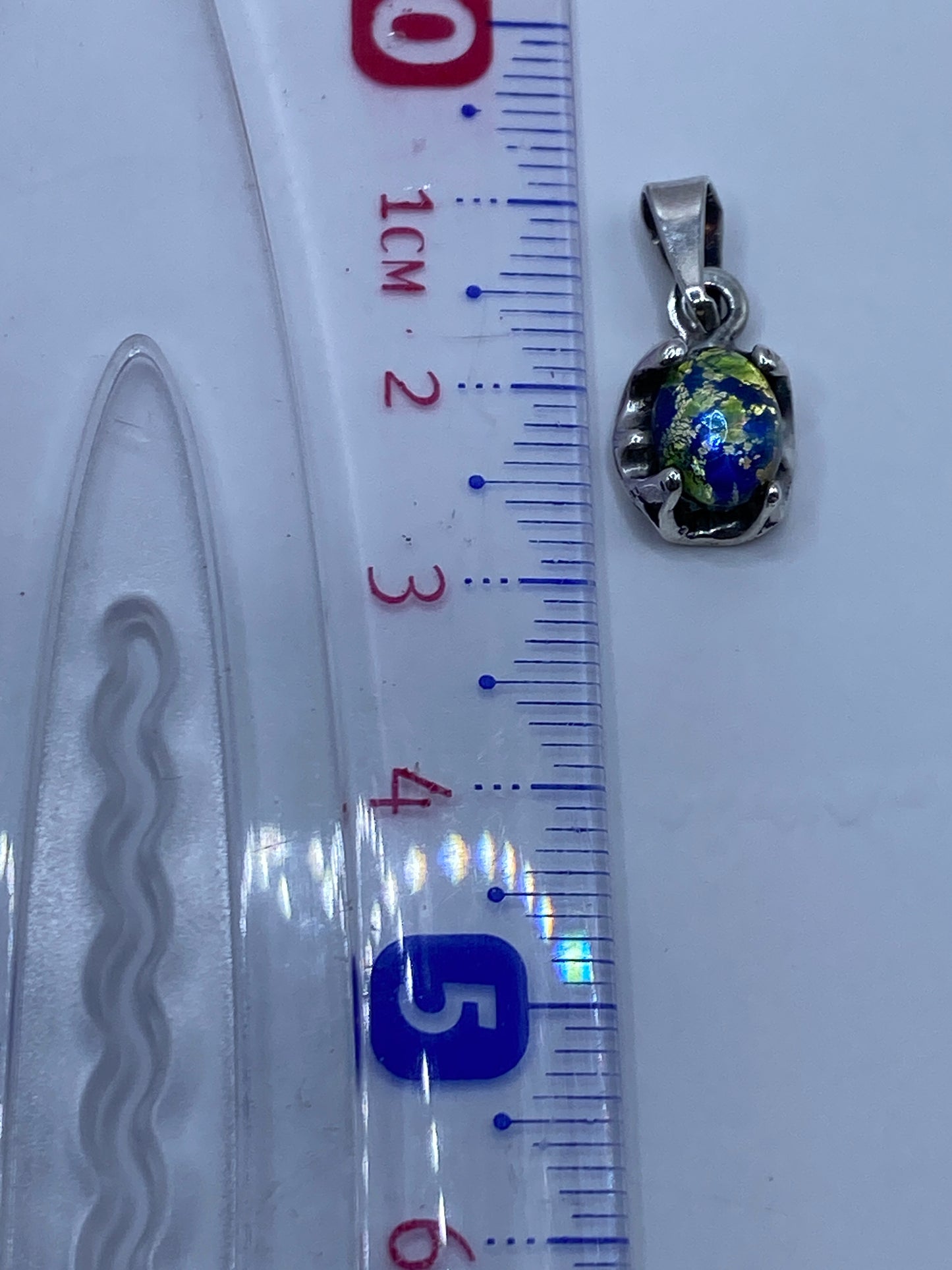 Dije de plata multicolor en la mano de una mujer luciendo su color