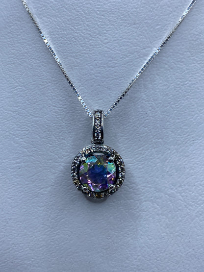 Dije de plata con circonia multicolor facetada, colgado de cadena, reflejando luz en tonos púrpura, verde y azul