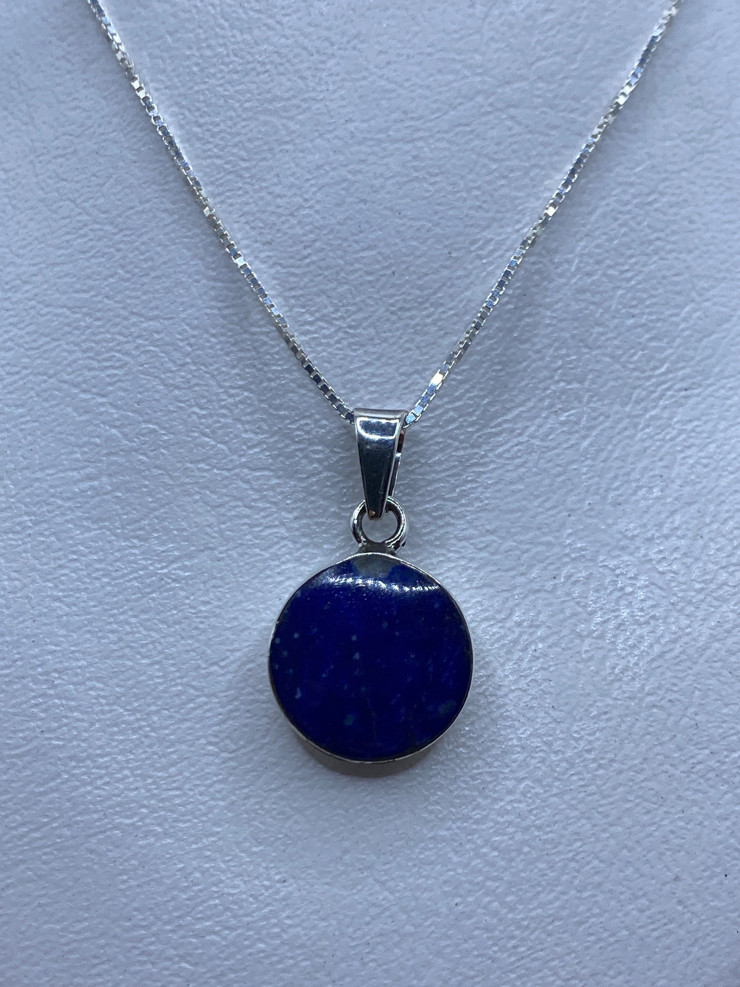 Dije de plata con piedra azul engastada a mano, sobre cadena plateada