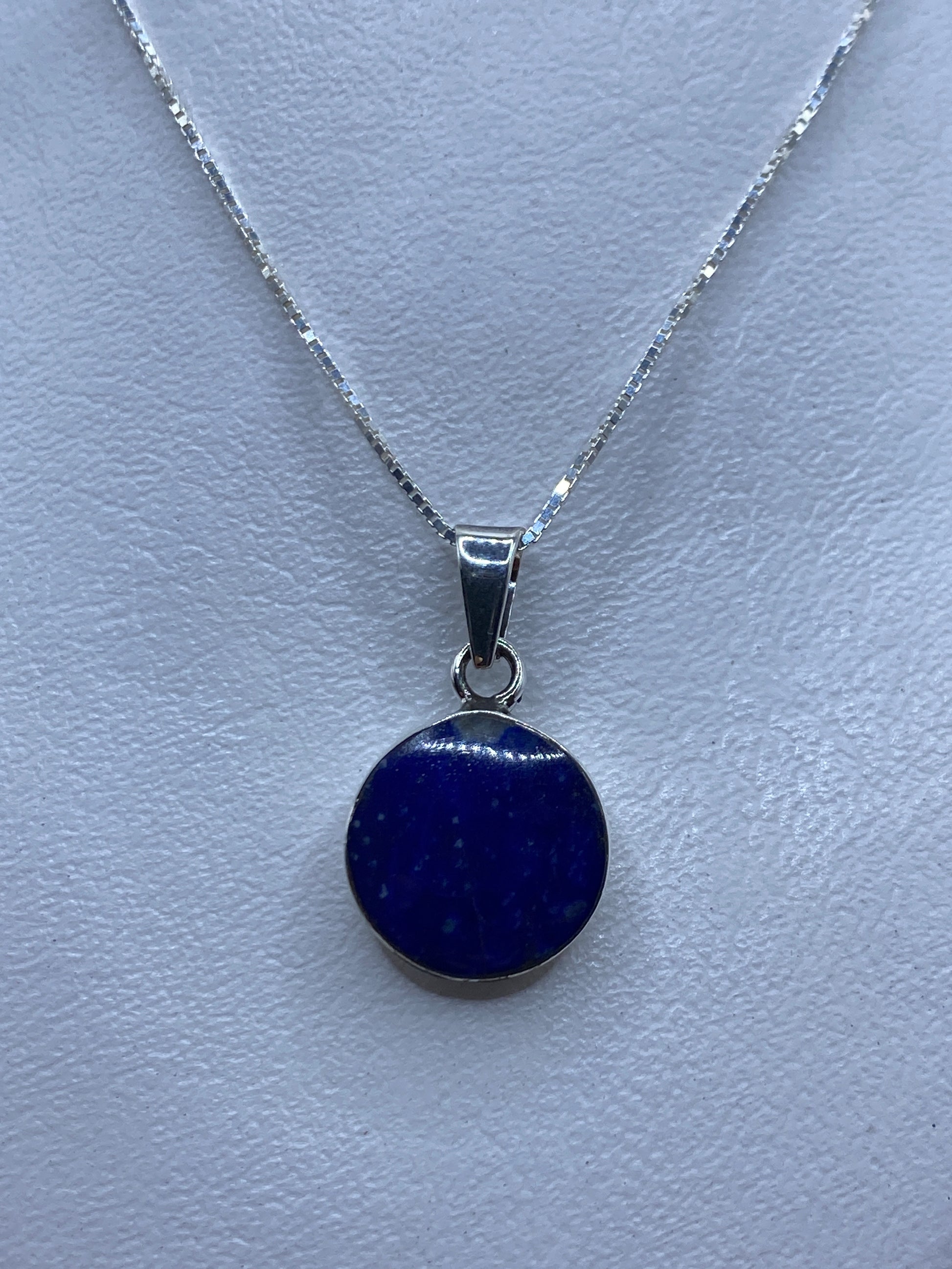 Dije de plata con piedra azul engastada a mano, sobre cadena plateada