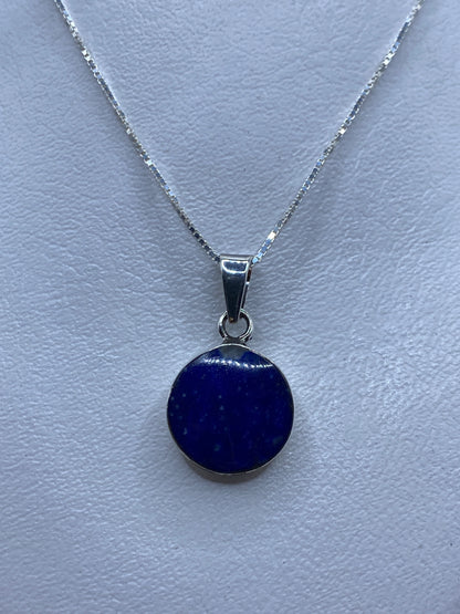 Dije de plata con piedra azul engastada a mano, sobre cadena plateada