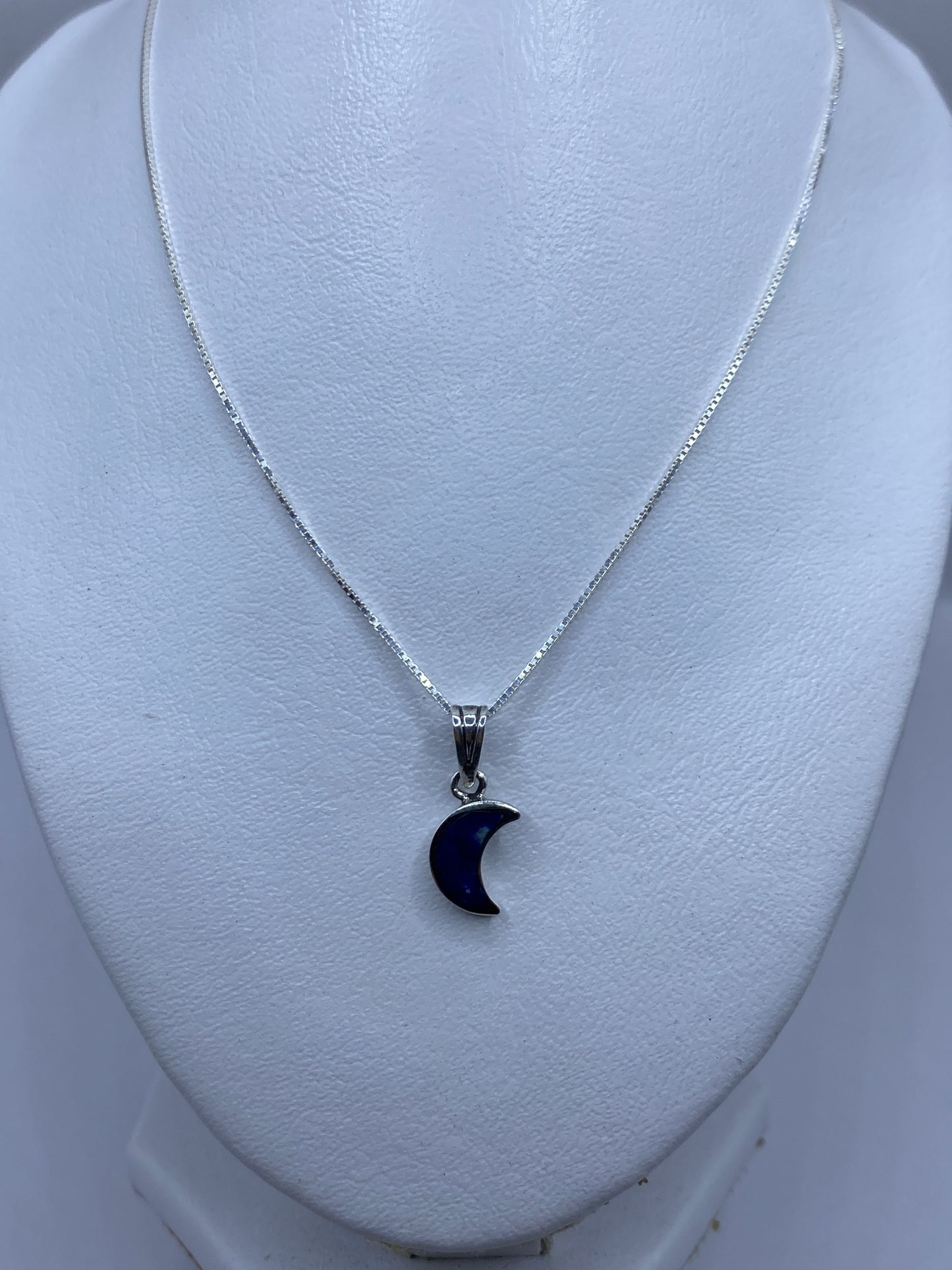 Dije luna colgando de cadena de plata, sobre piel