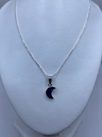 Dije luna colgando de cadena de plata, sobre piel