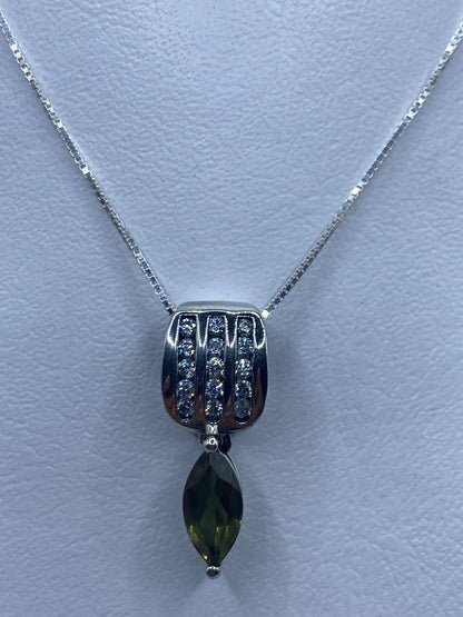 Dije de plata con circonia verde olivo en forma geométrica colgando de cadena de plata