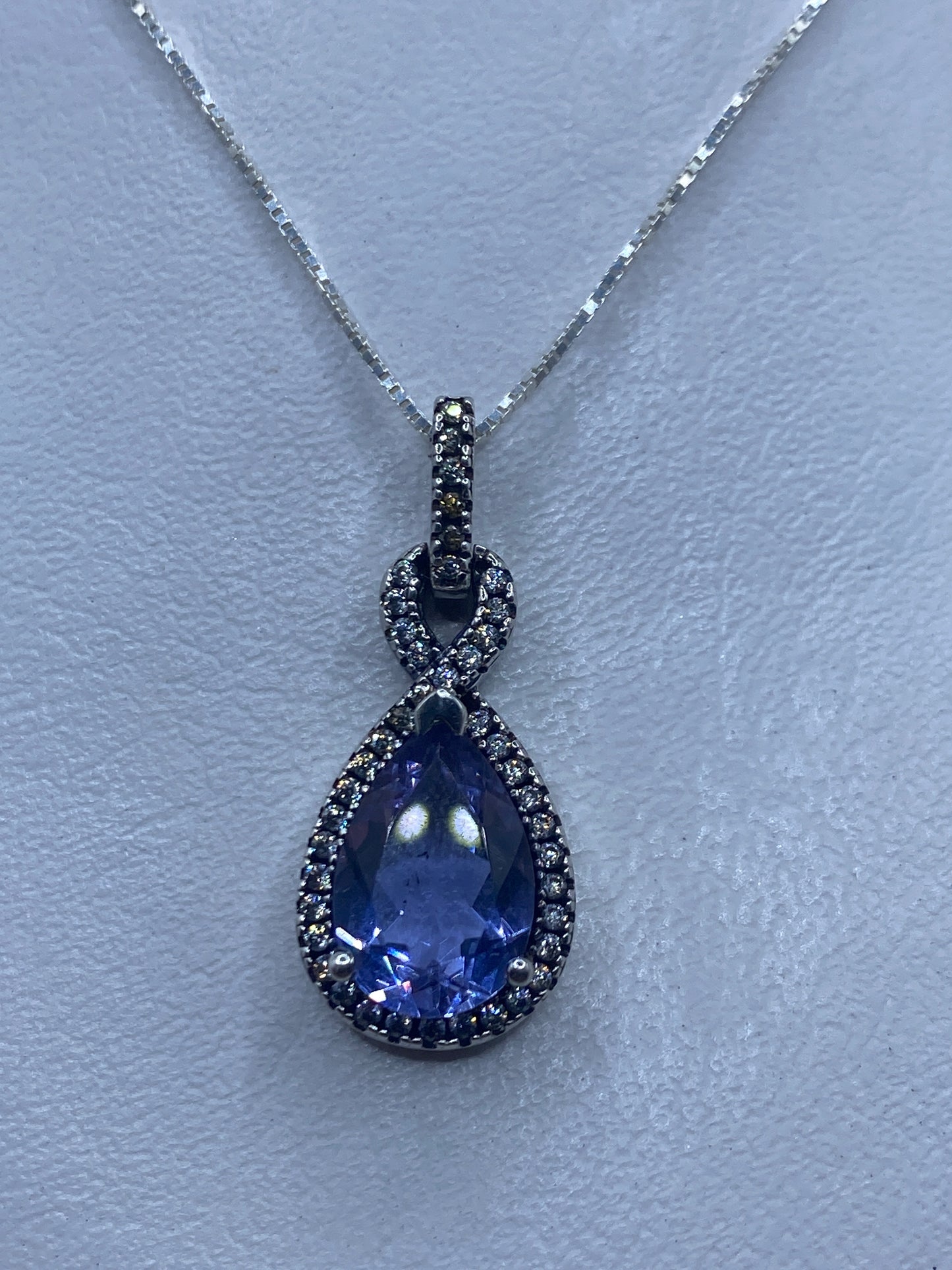 Dije de plata .925 con circonia lavanda sobre cadena delgada, colgando sobre fondo blanco