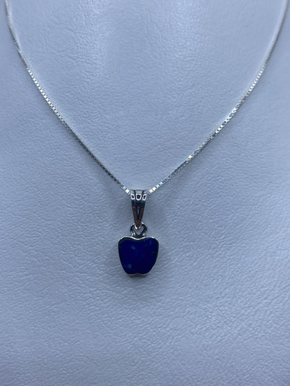 Dije de plata con piedra azul engastada, colgando de cadena delgada