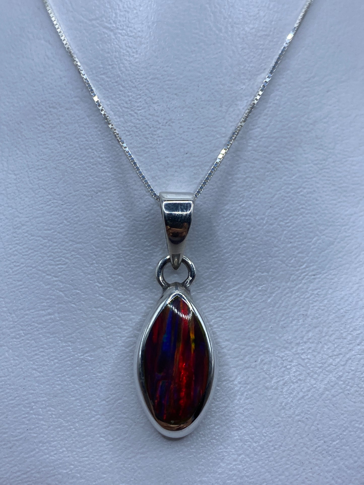 Dije de plata .950 con ópalo de fuego multicolor en tonos rojo, naranja y amarillo, colgado de una fina cadena de plata