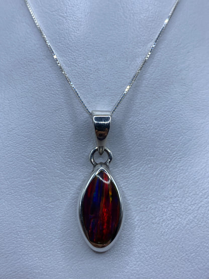 Dije de plata .950 con ópalo de fuego multicolor en tonos rojo, naranja y amarillo, colgado de una fina cadena de plata