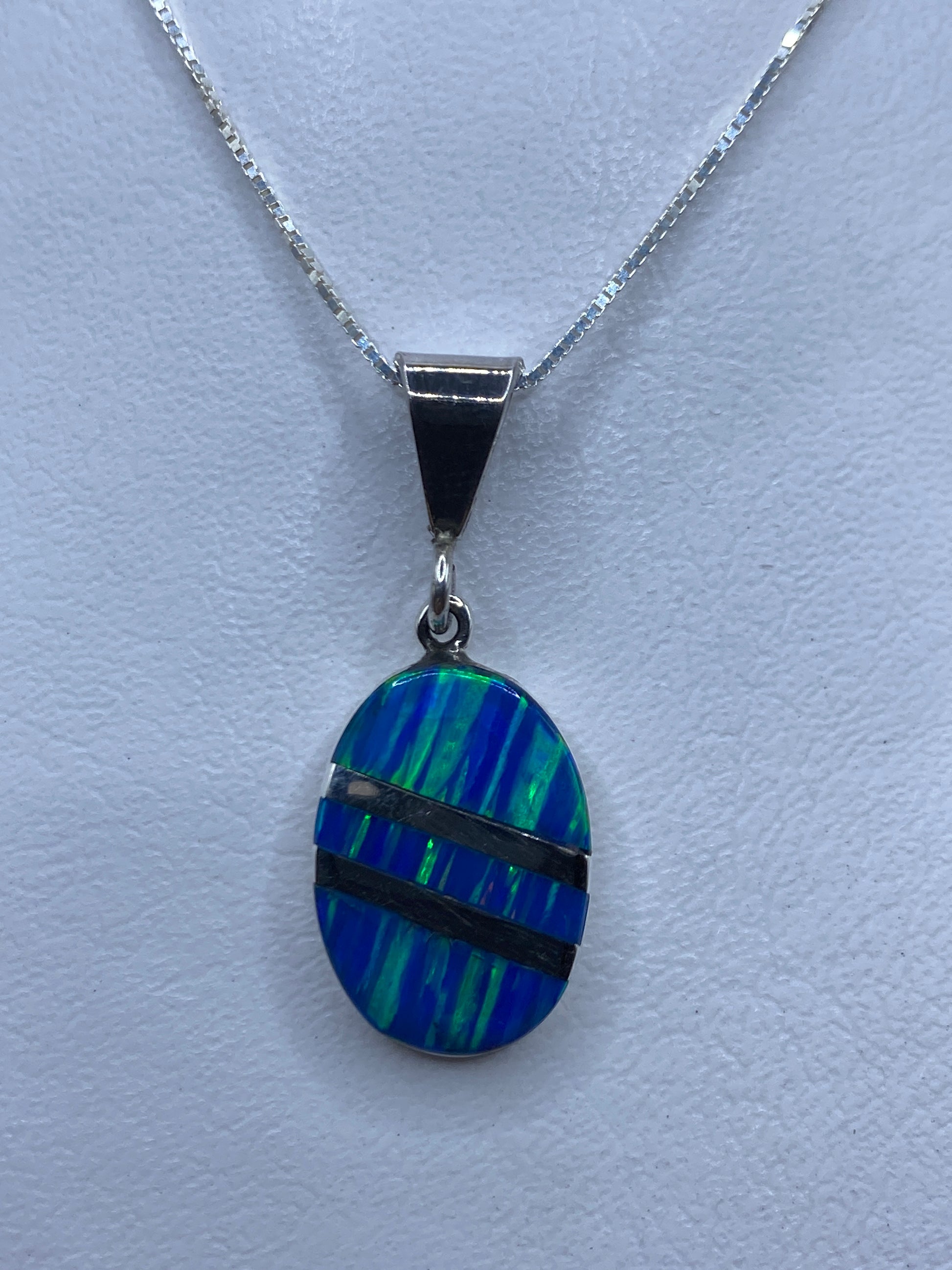 Dije de plata con ópalo de fuego azul, 4 cm, sobre fondo blanco