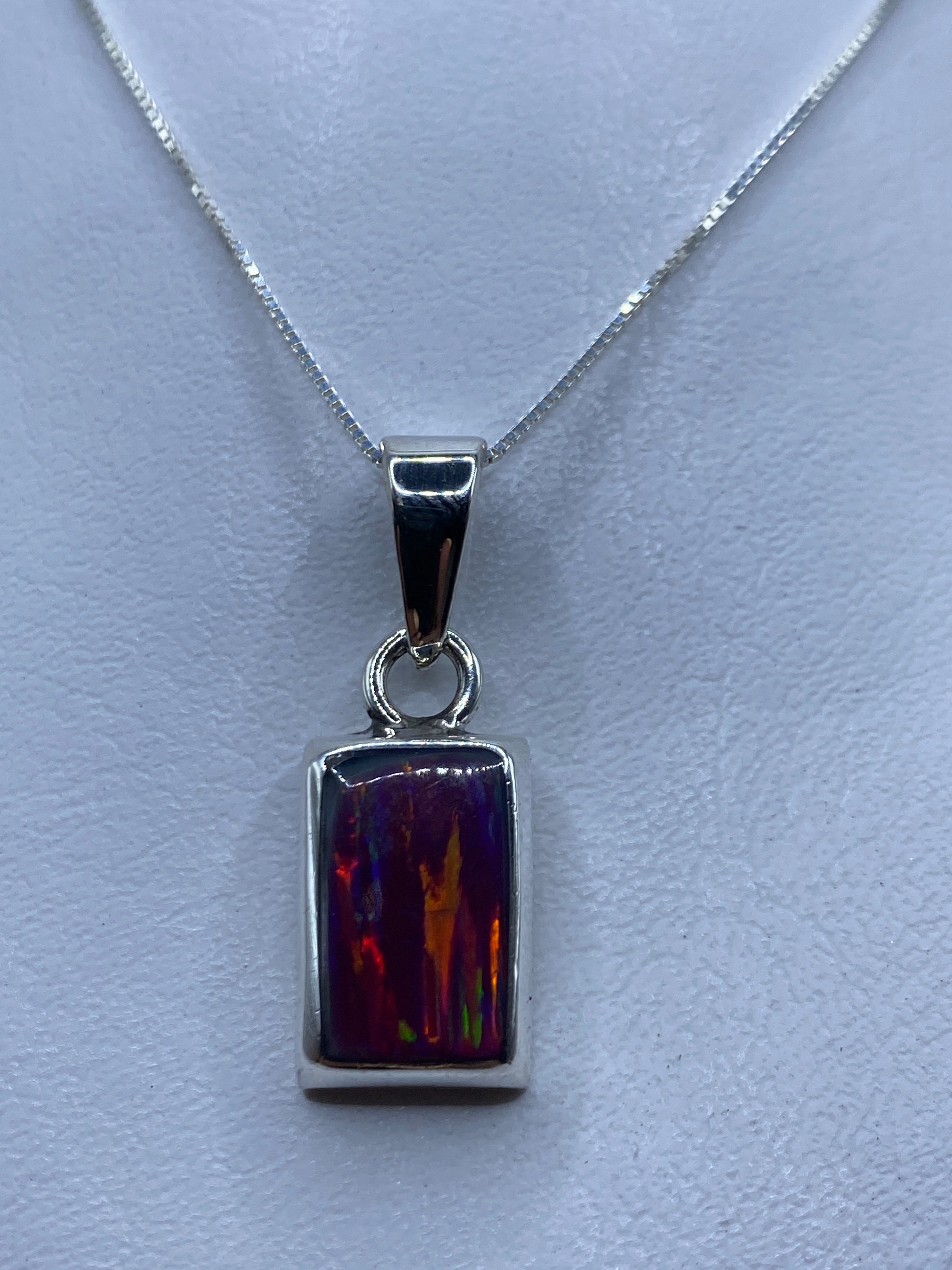 Dije de plata rectangular con ópalo de fuego en tonalidades rosa, naranja y dorado sobre cadena plateada