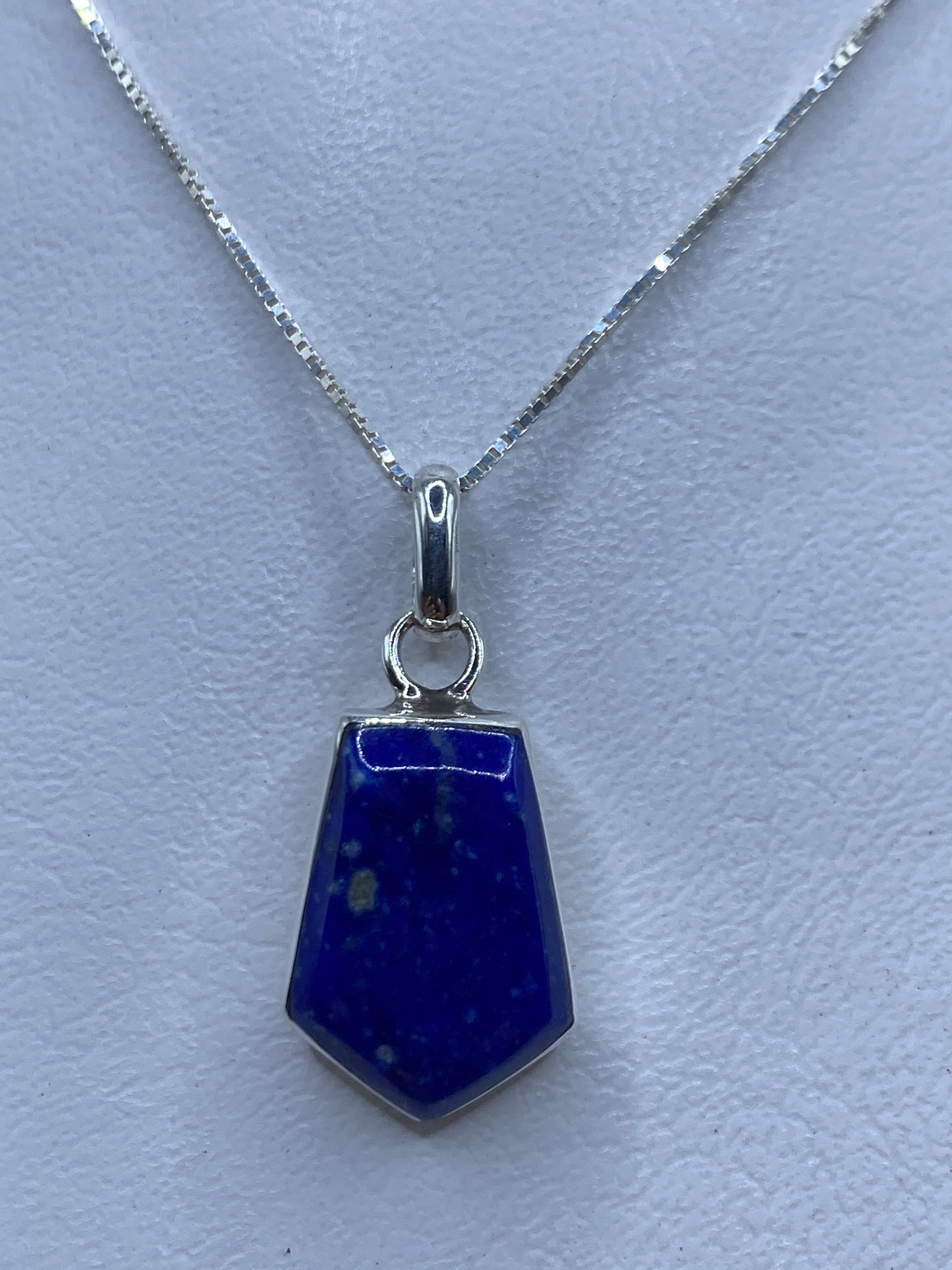 Dije de plata con piedra azul engastada, colgante sobre cadena delicada