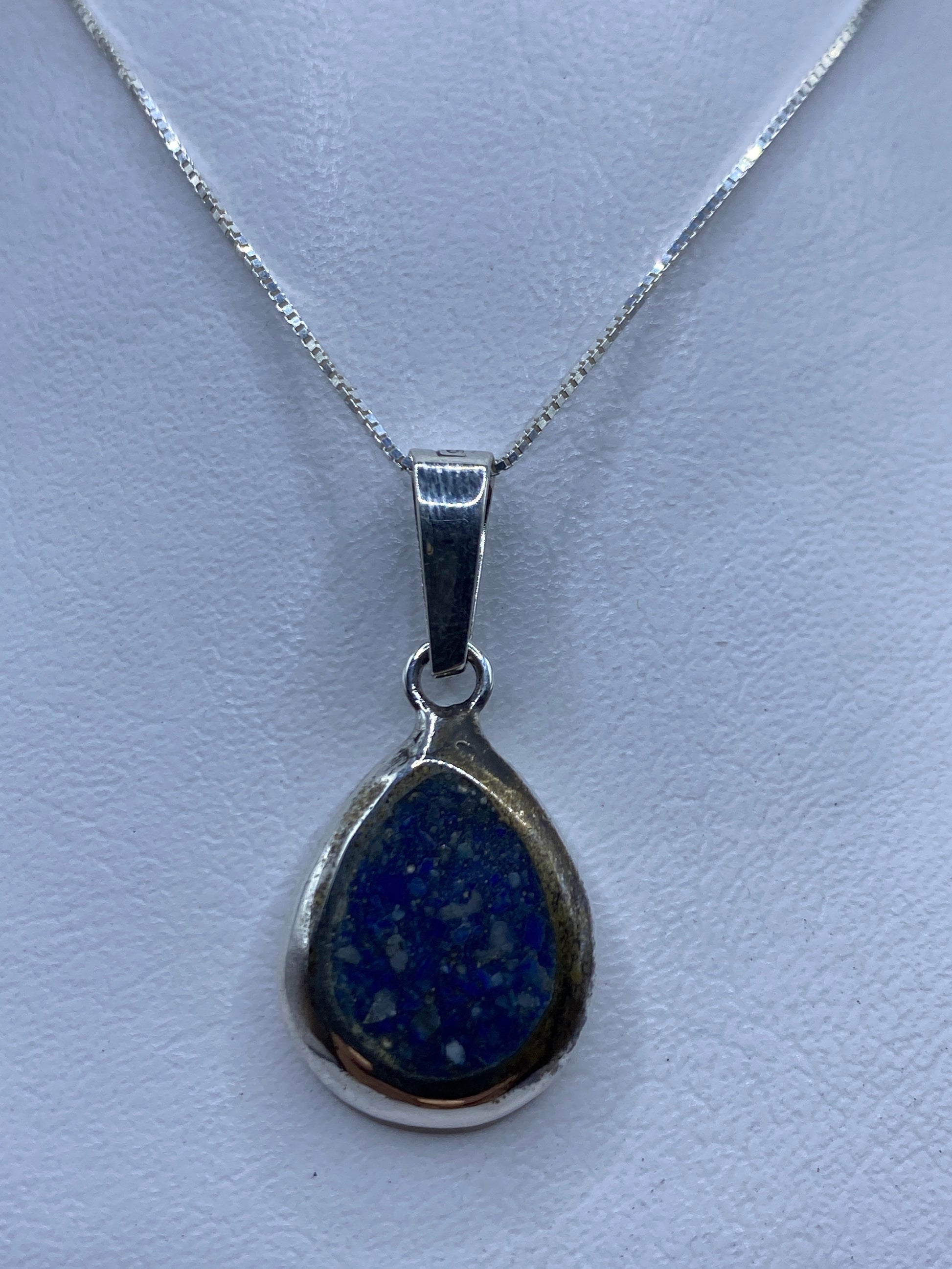 Dije de plata .925 con piedra azul engastada, colgando de una cadena fina