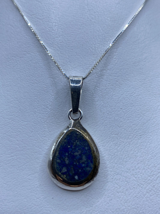 Dije de plata .925 con piedra azul engastada, colgando de una cadena fina