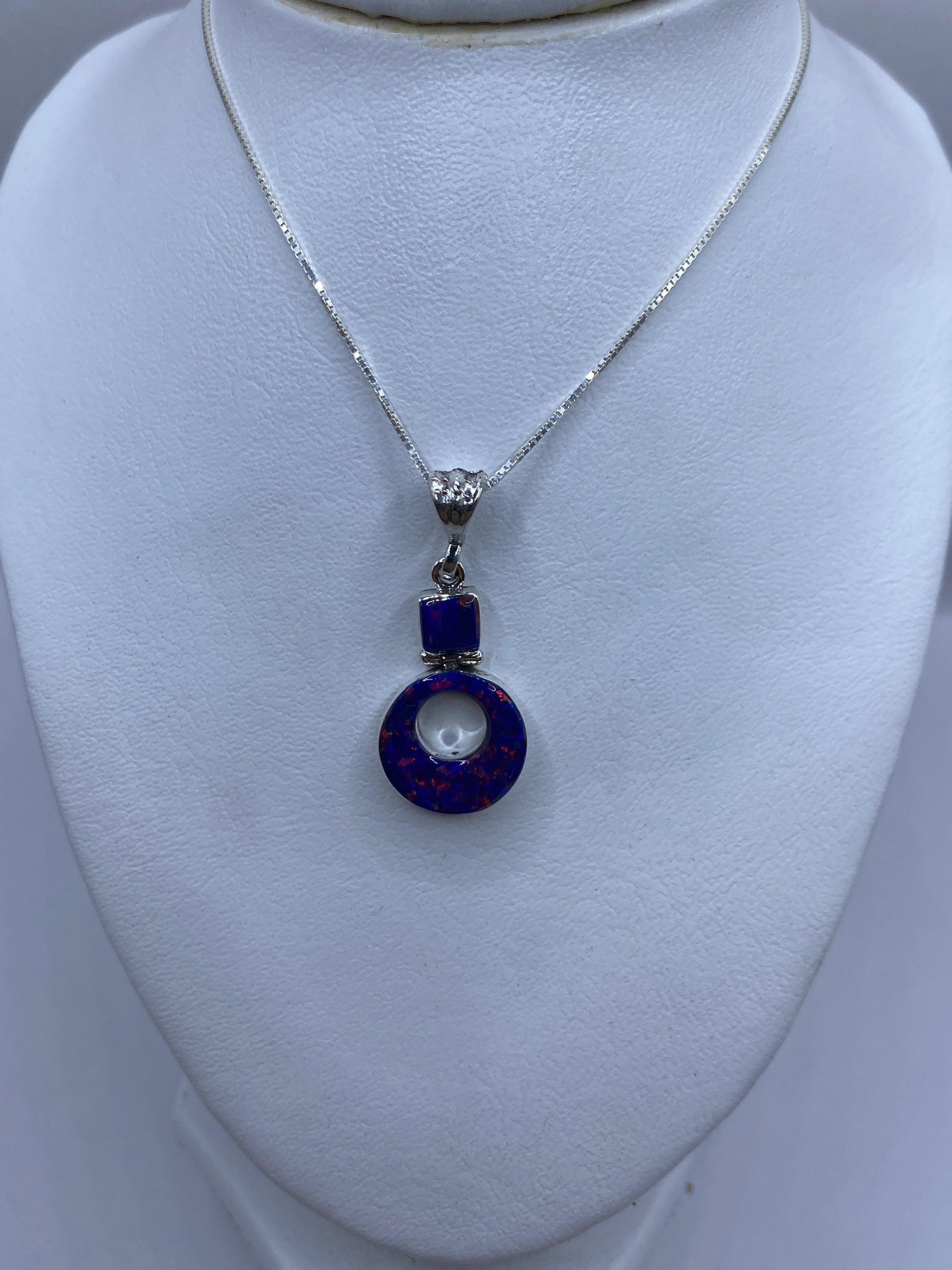 Dije redondo de plata con piedra azul y baño plateado, vista lateral