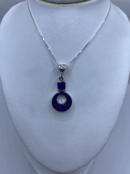 Dije redondo de plata con piedra azul y baño plateado, vista lateral