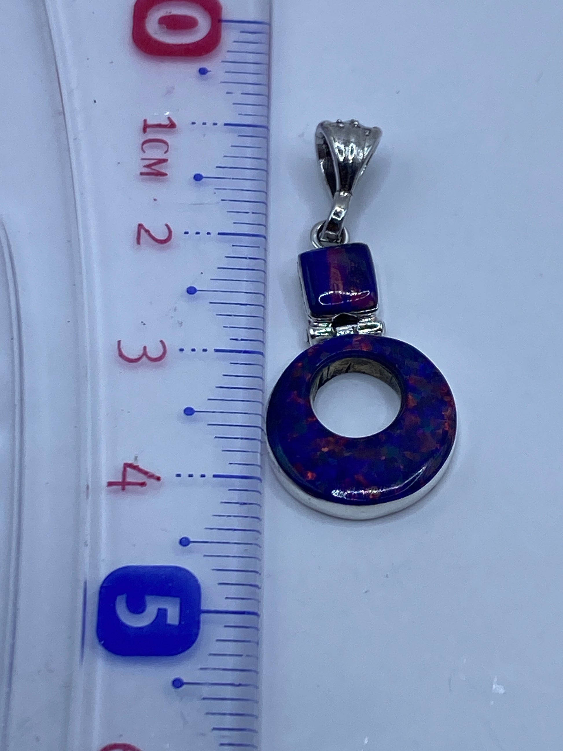 Medición del dije de 4.1 cm en regla, mostrando Quinto de .950 en el reverso