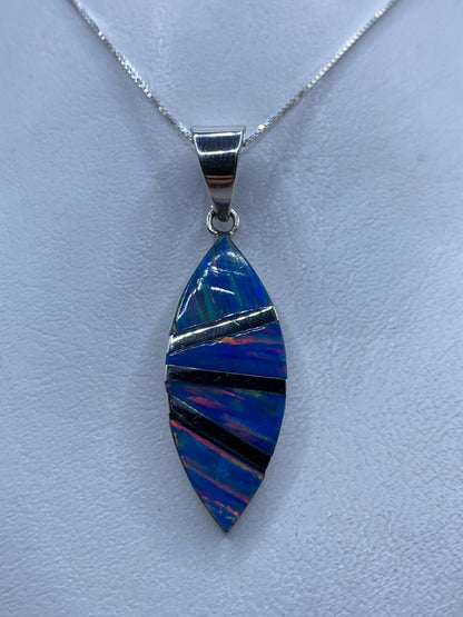 Dije de plata con ópalo de fuego azul incrustado a mano, colgando de cadena en cuello
