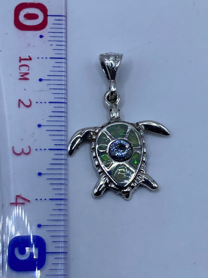 Dije de tortuga sobre fondo blanco mostrando los colores del ópalo