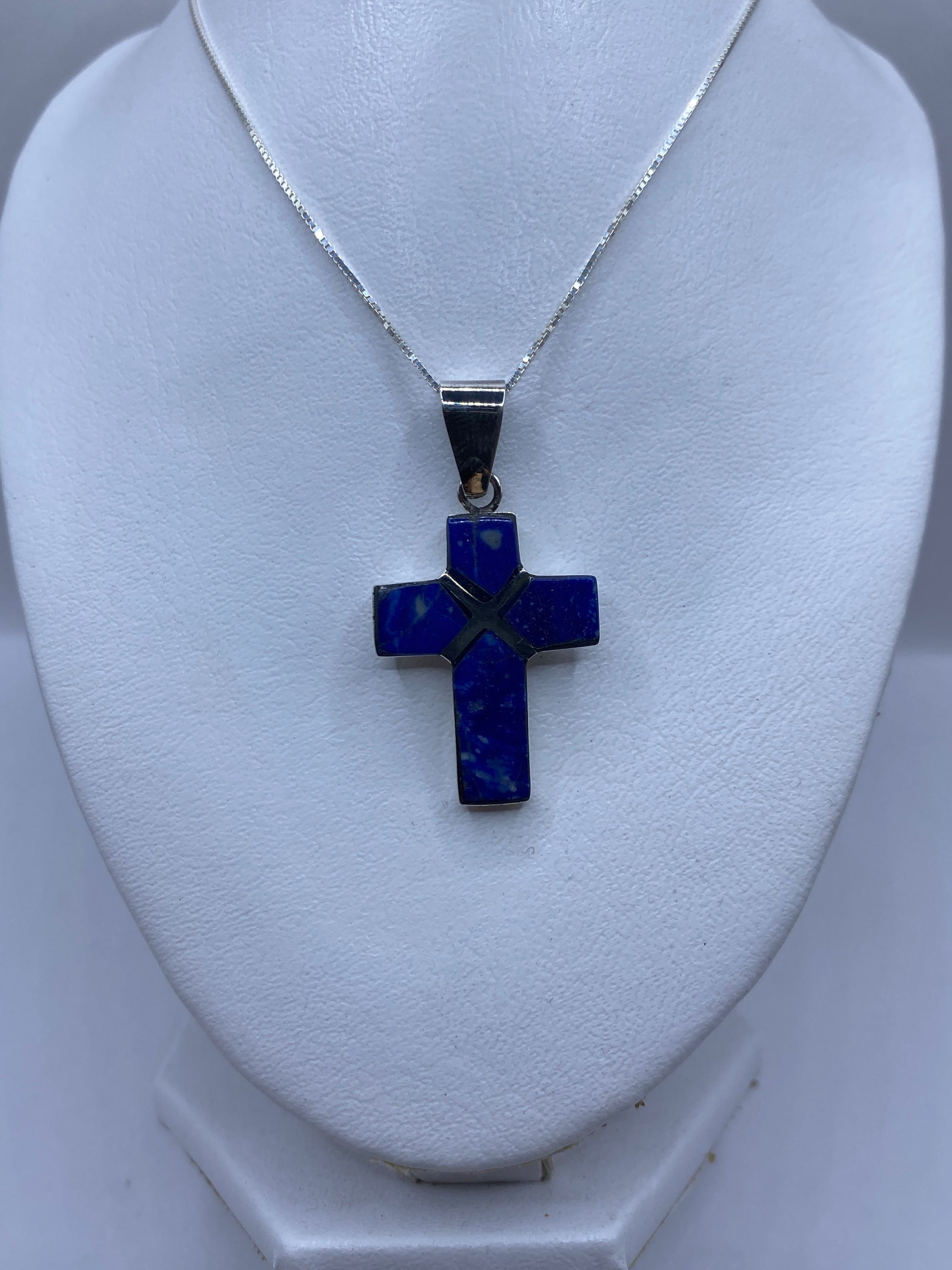 Dije cruz religiosa de plata pura mostrando el detalle del lapislázuli incrustado