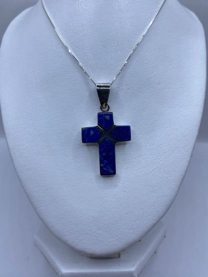 Dije cruz religiosa de plata pura mostrando el detalle del lapislázuli incrustado