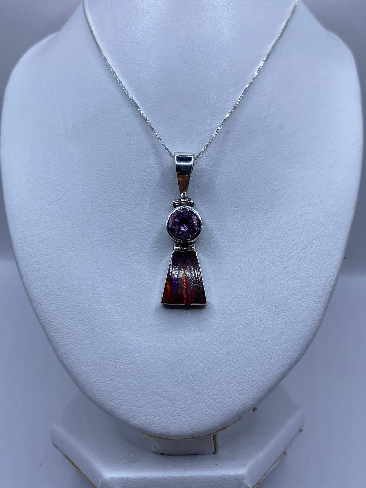 Detalle del ópalo multicolor engastado en plata, mostrando los tonos rojo, naranja y amarillo