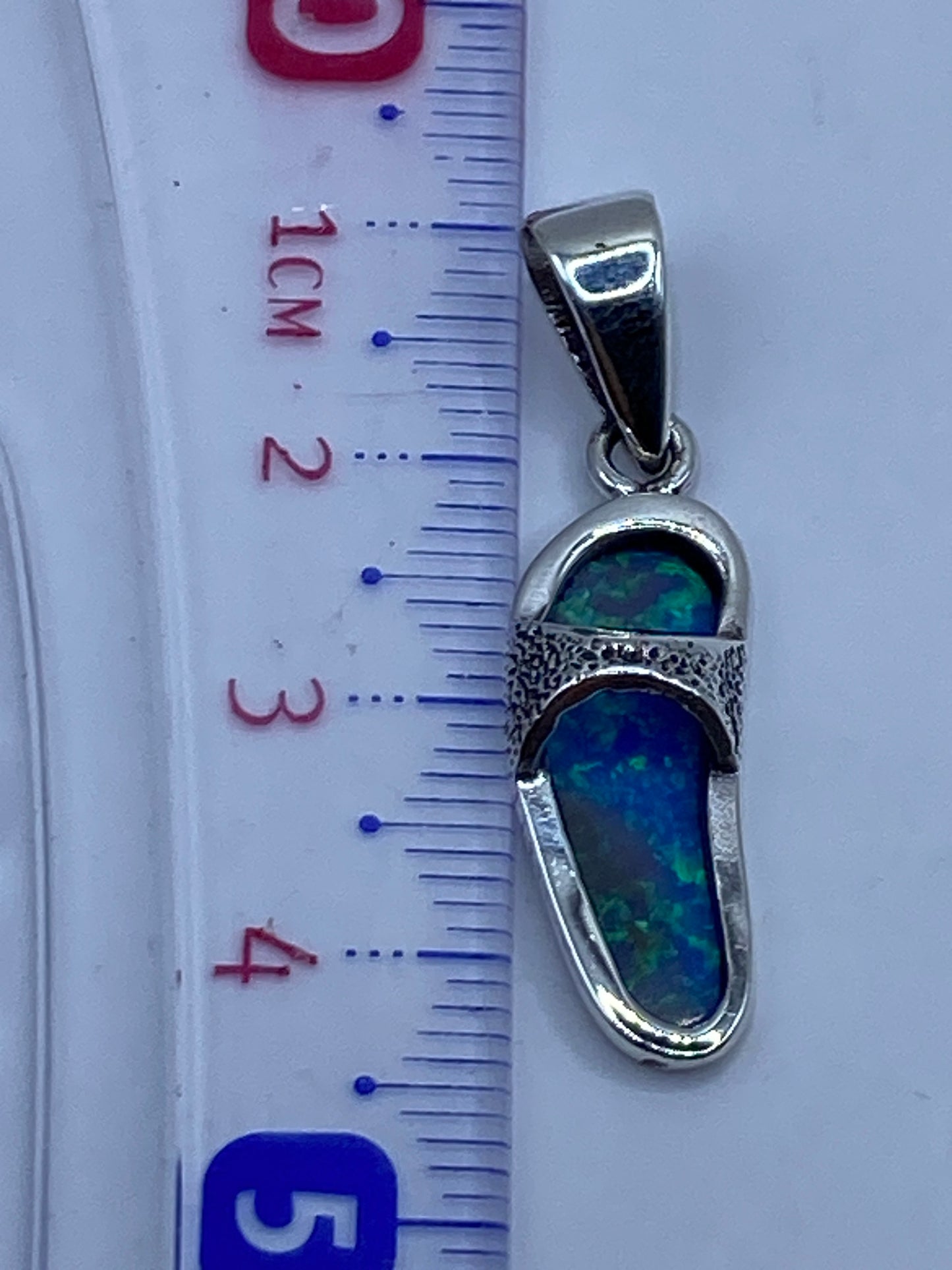 Dije de 4.4 cm sobre regla de medición, mostrando tamaño compacto