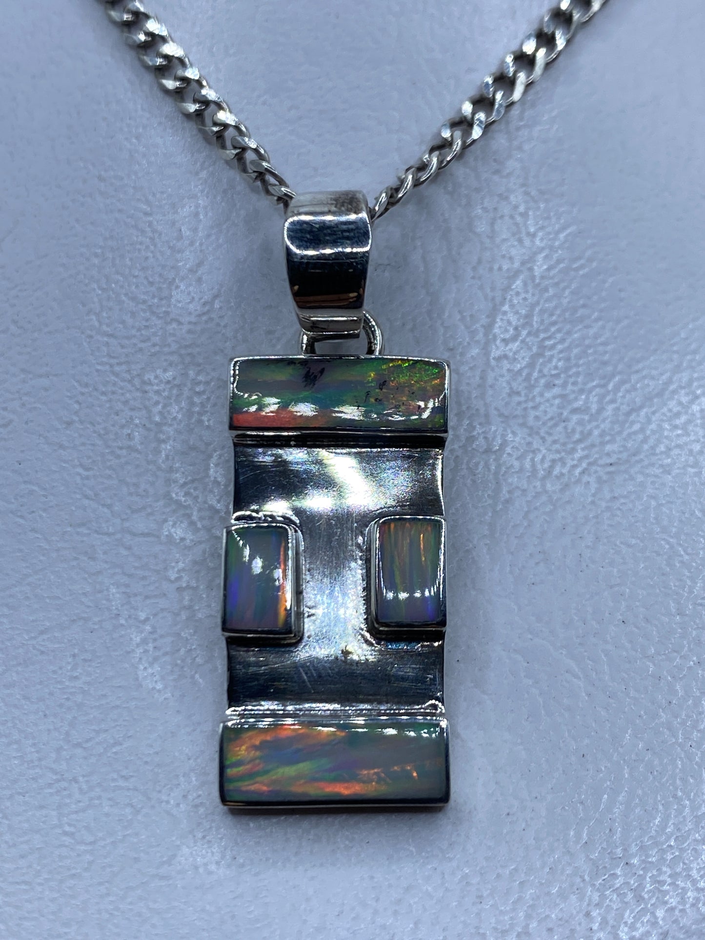 Dije de plata .950 rectangular con ópalo de fuego y dos engastes geométricos sobre fondo claro
