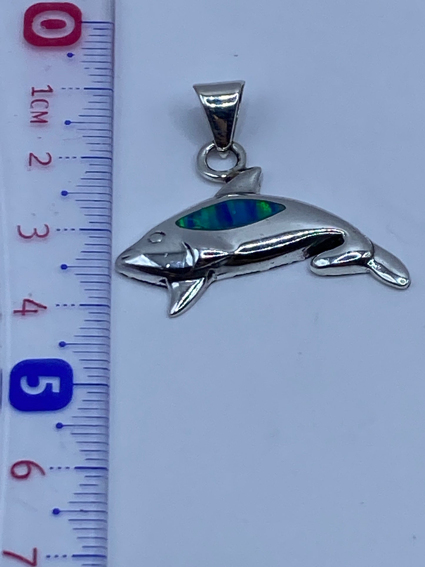 Dije orca de plata sobre fondo gris mostrando el Quinto .925