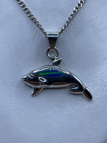 Dije de plata ballena jorobada con ópalo de fuego azul en la mano