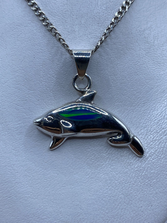 Dije de plata ballena jorobada con ópalo de fuego azul en la mano