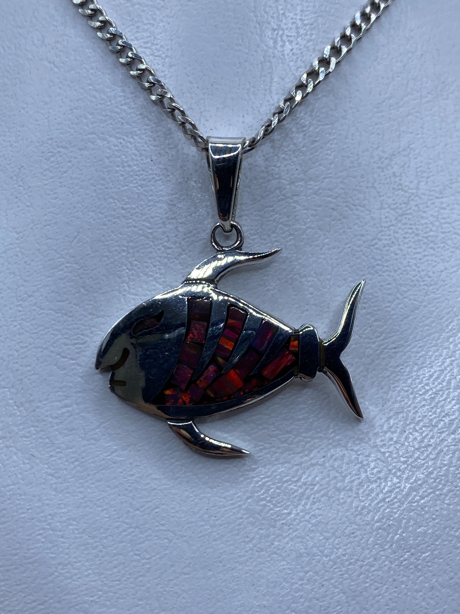 Dije pez de plata .950 con ópalo de fuego multicolor incrustado, colgando de una cadena eslabón