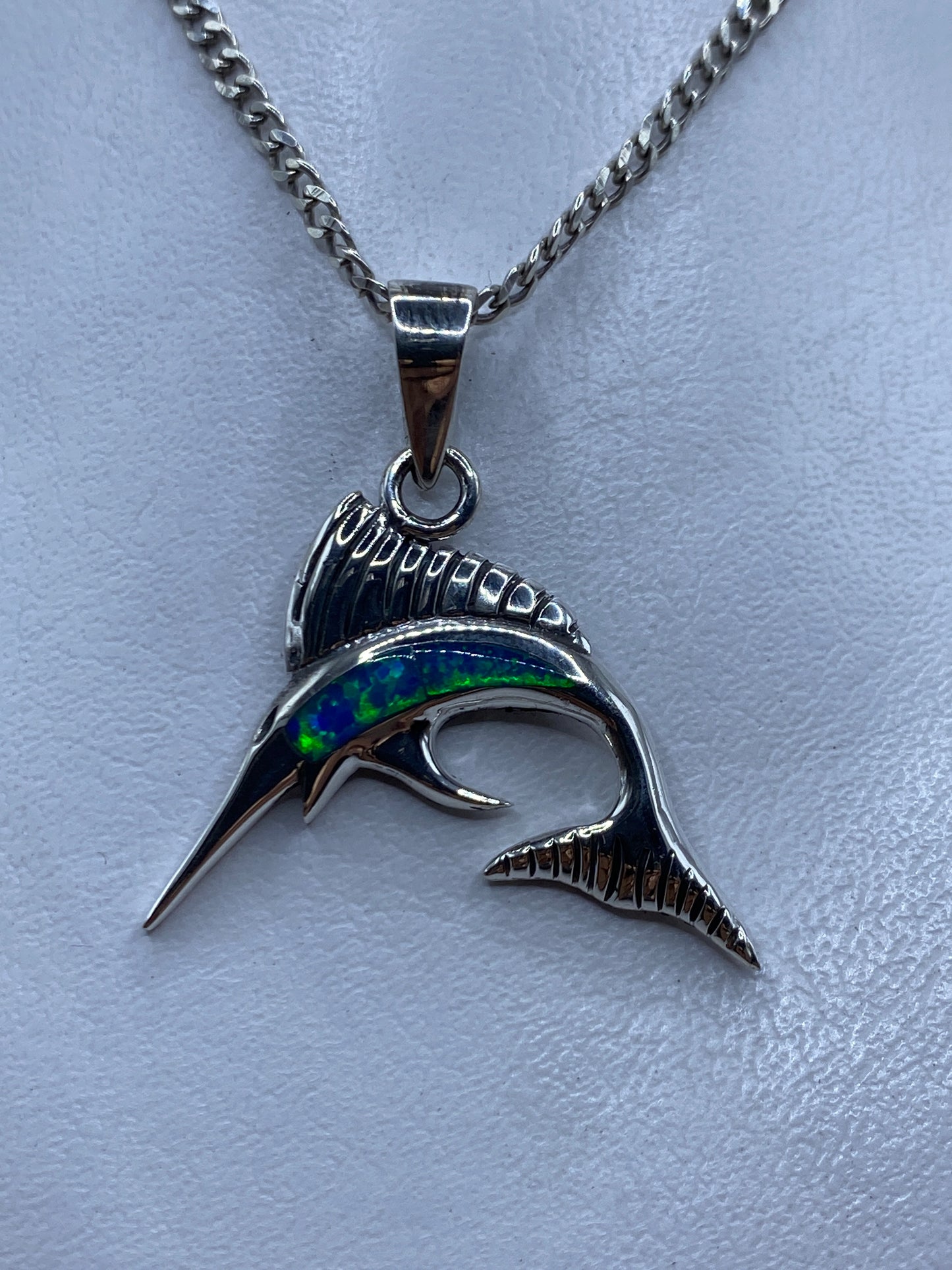 Dije de plata .950 con forma de marlin y opalo de fuego azul, colgando de cadena en el pecho